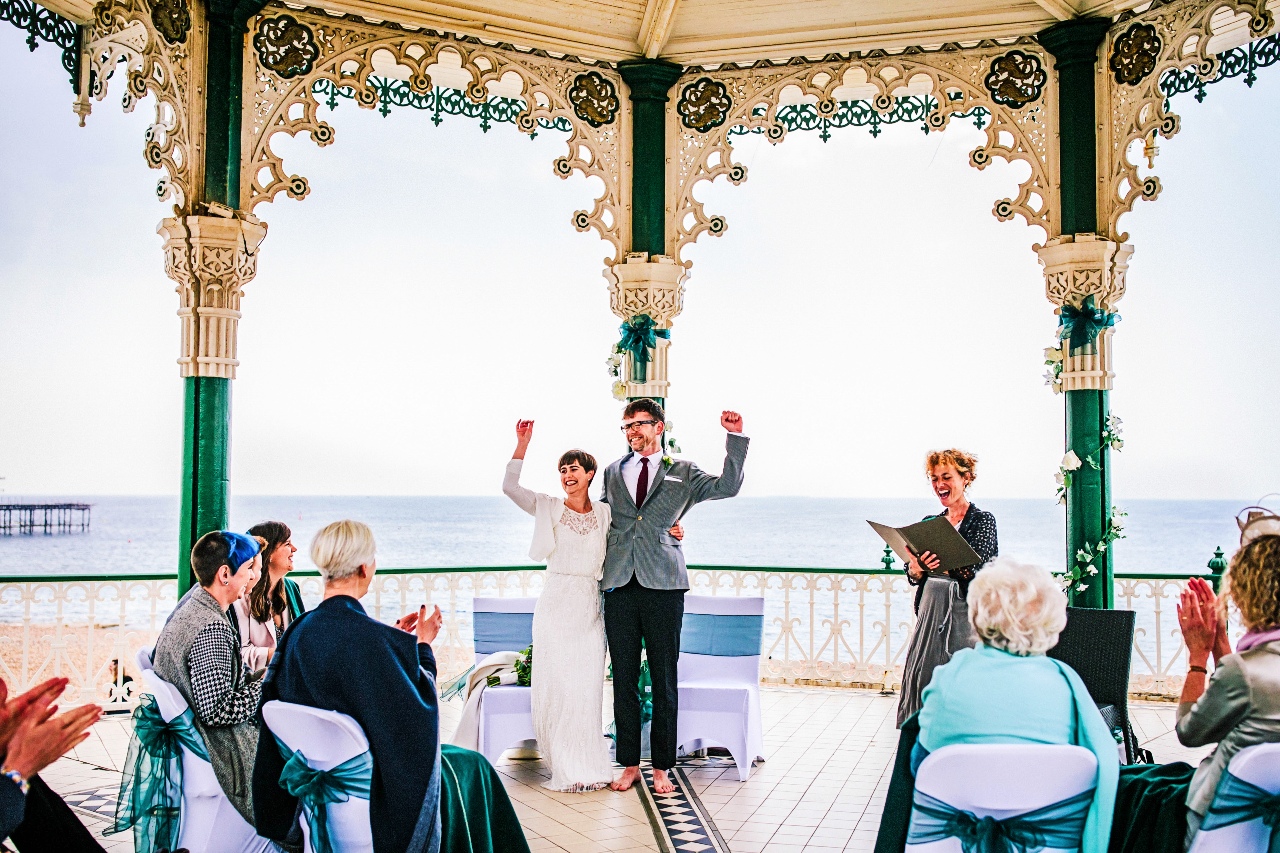 A joyful couple with their arms in the air at their wedding ceremony.